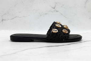 Evani Black Cowrie Shell Raffia Flat Slide Sandals – side profile view on white marble