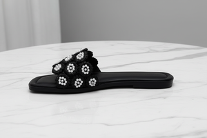 Tavo Black Pearl Flower Flat Slide Sandals – side profile view on white marble