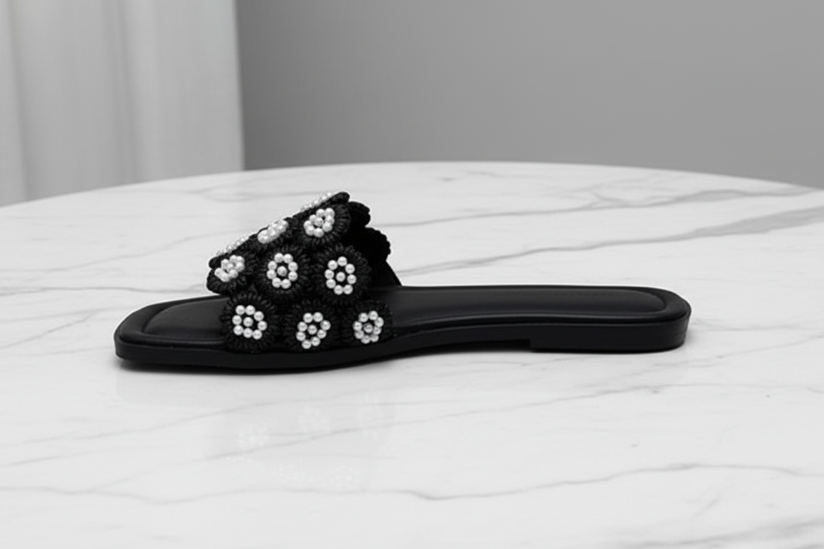 Tavo Black Pearl Flower Flat Slide Sandals – side profile view on white marble
