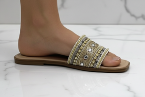 Zuri Nude Gold Embroidered Crystal Flat Slide Sandals – ground level profile hero shot showing gold embroidery and crystal jewel detail mid-stride