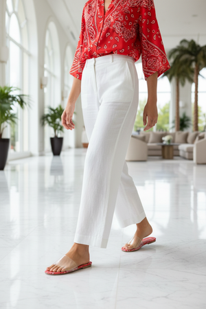 Sierra Red Bandana Paisley Print Clear Strap Flat Slide Sandals – model walking in marble hotel lobby in white wide-leg trousers and red silk blouse