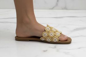 Tavo Nude Pearl Flower Raffia Flat Slide Sandals – ground level profile hero shot showing pearl-centred raffia flower detail mid-stride